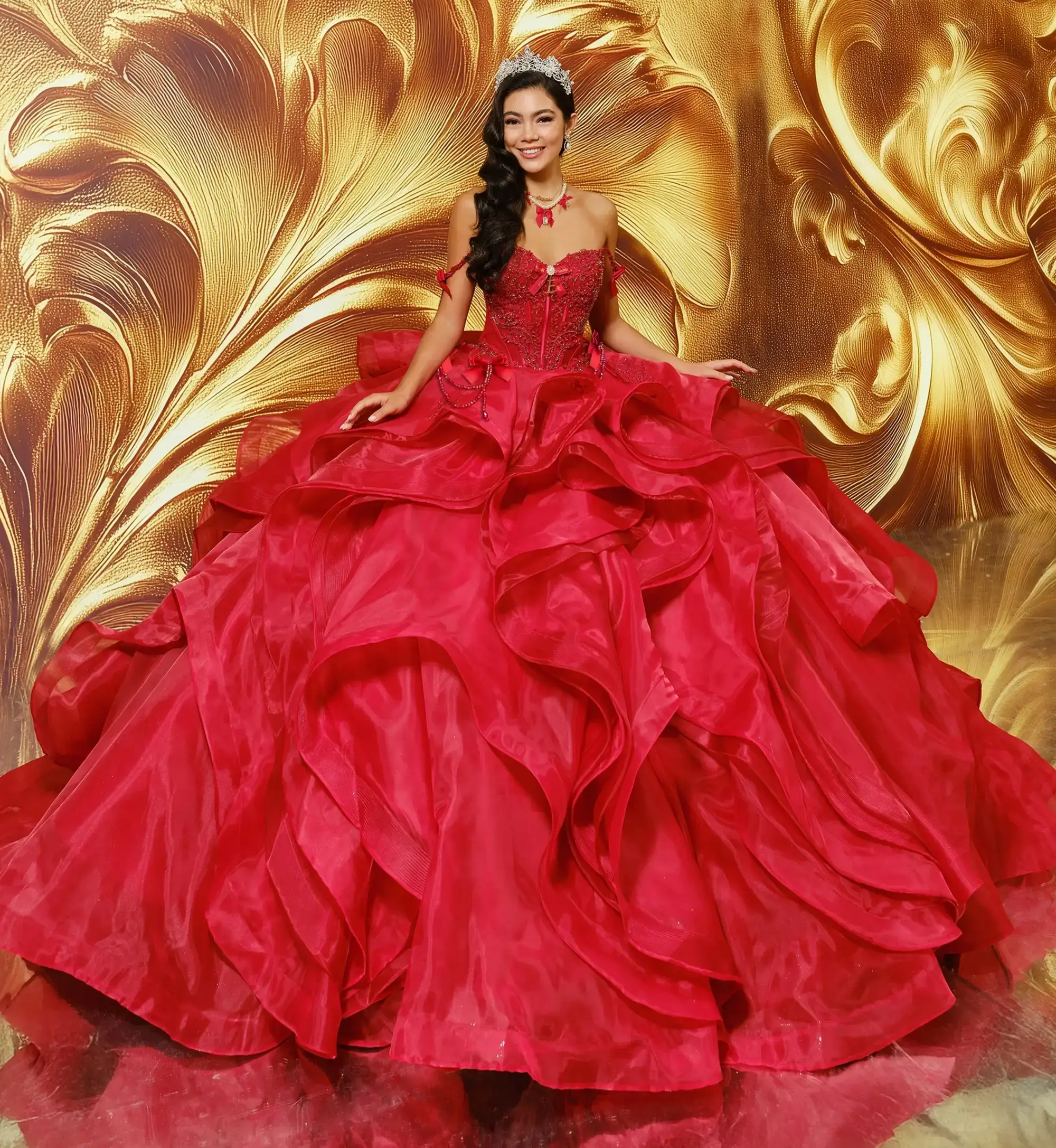 La modelo lleva un vestido rojo de quinceañera con hombros descubiertos.