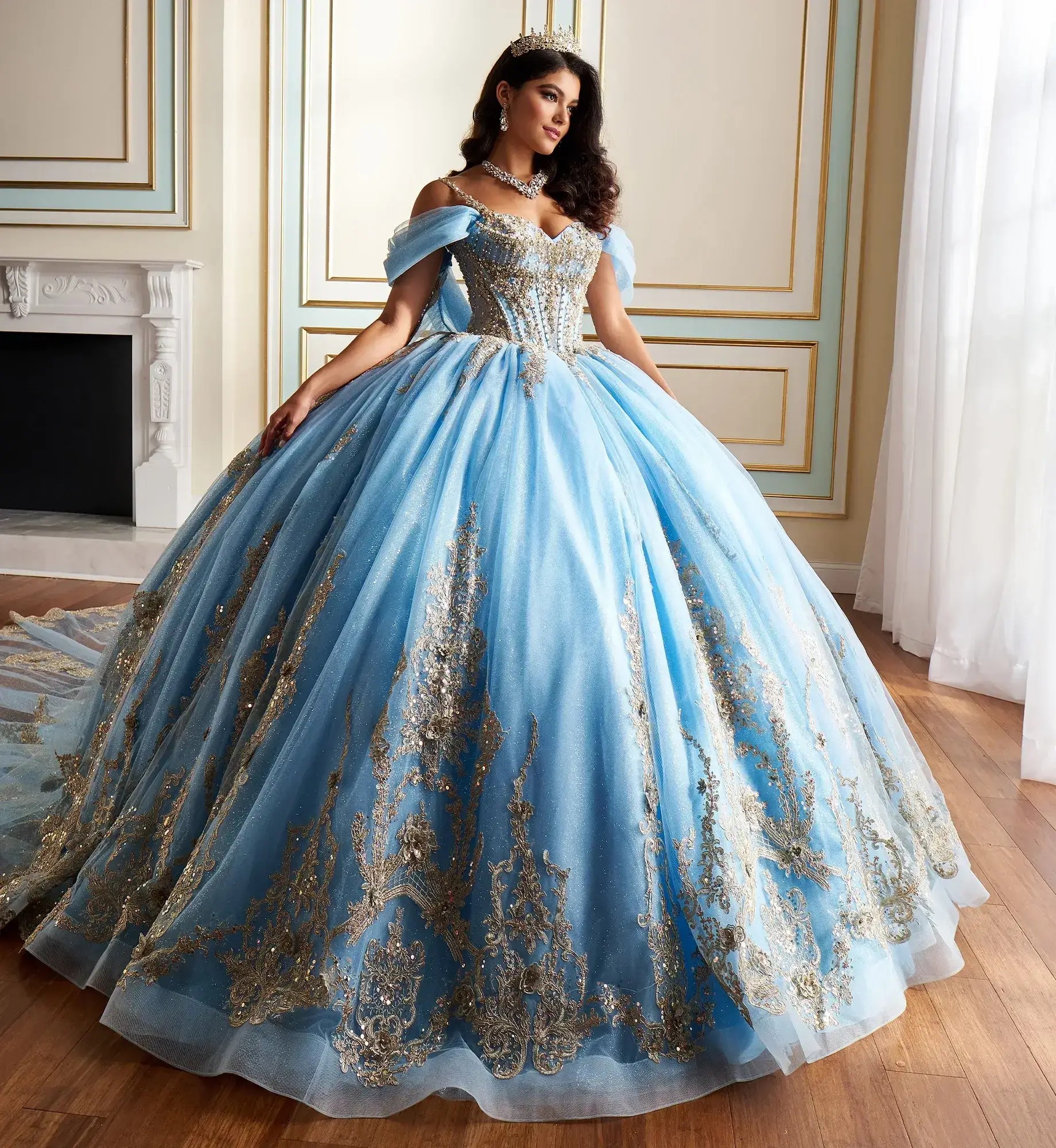 La modelo lleva un vestido de quinceañera azul claro con dorado y mangas caídas