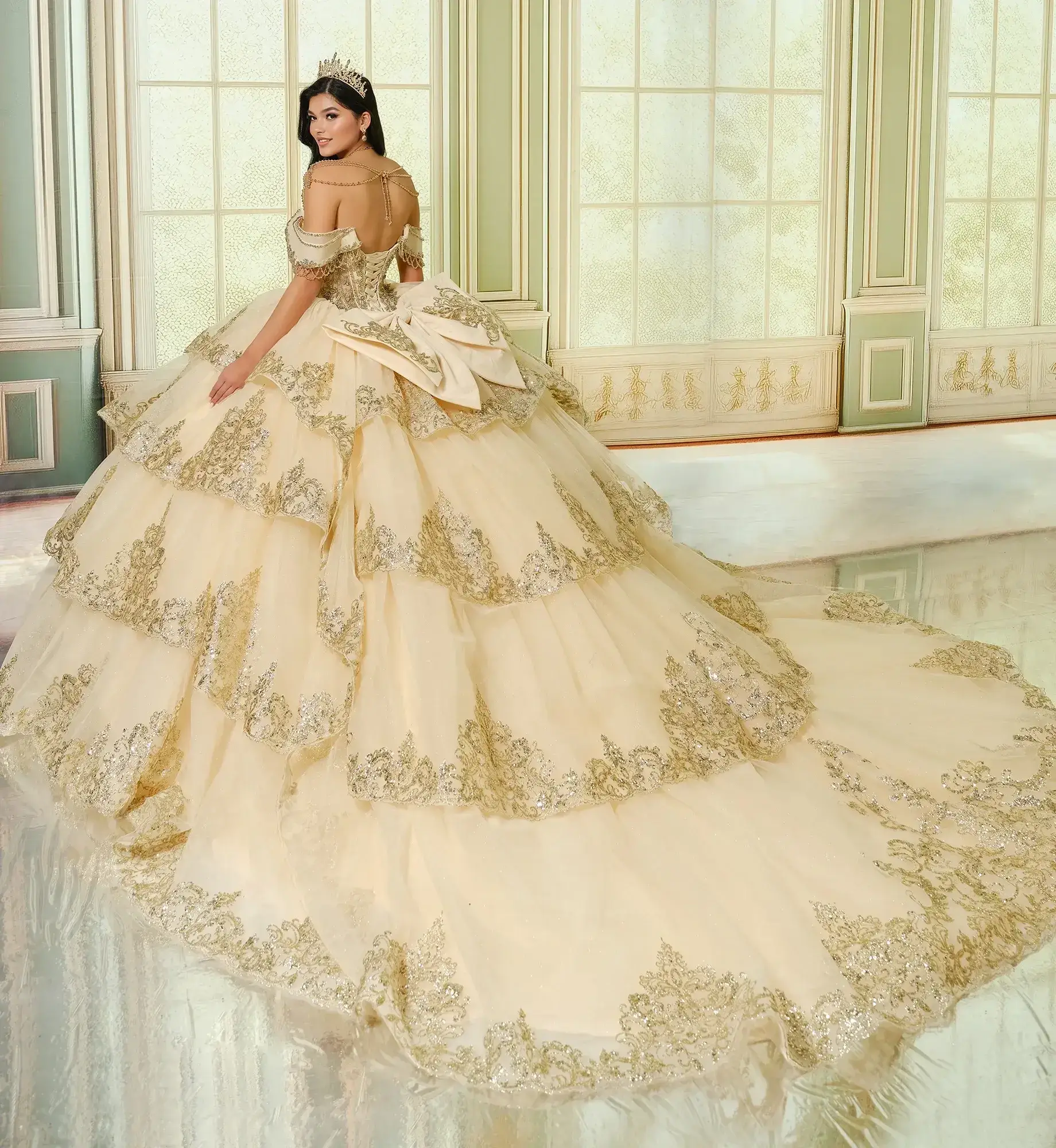 La modelo luce un vestido de quinceañera dorado champán con hombros descubiertos.