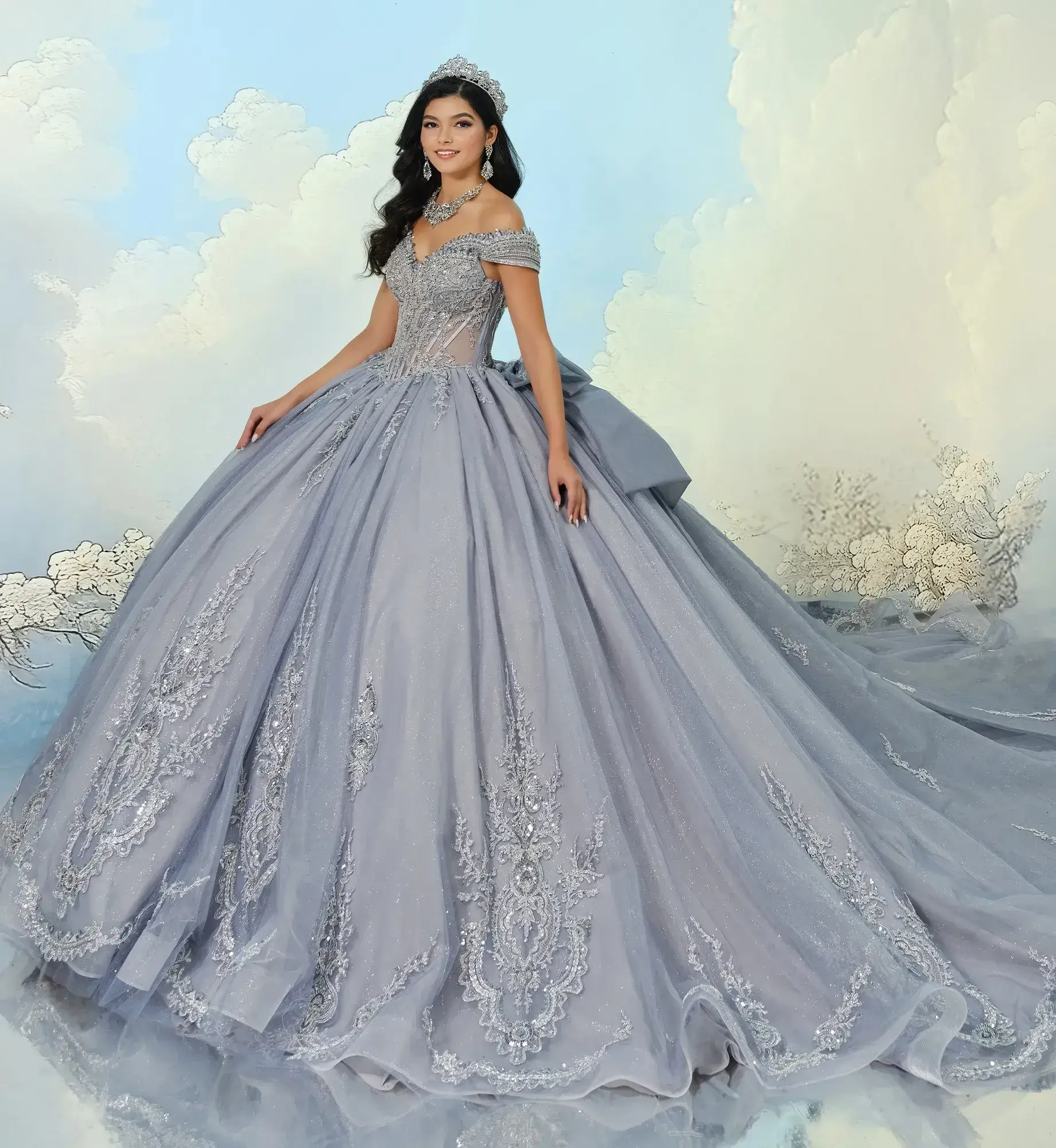 La modelo luce un vestido de quinceañera con hombros descubiertos y efecto niebla plateada.