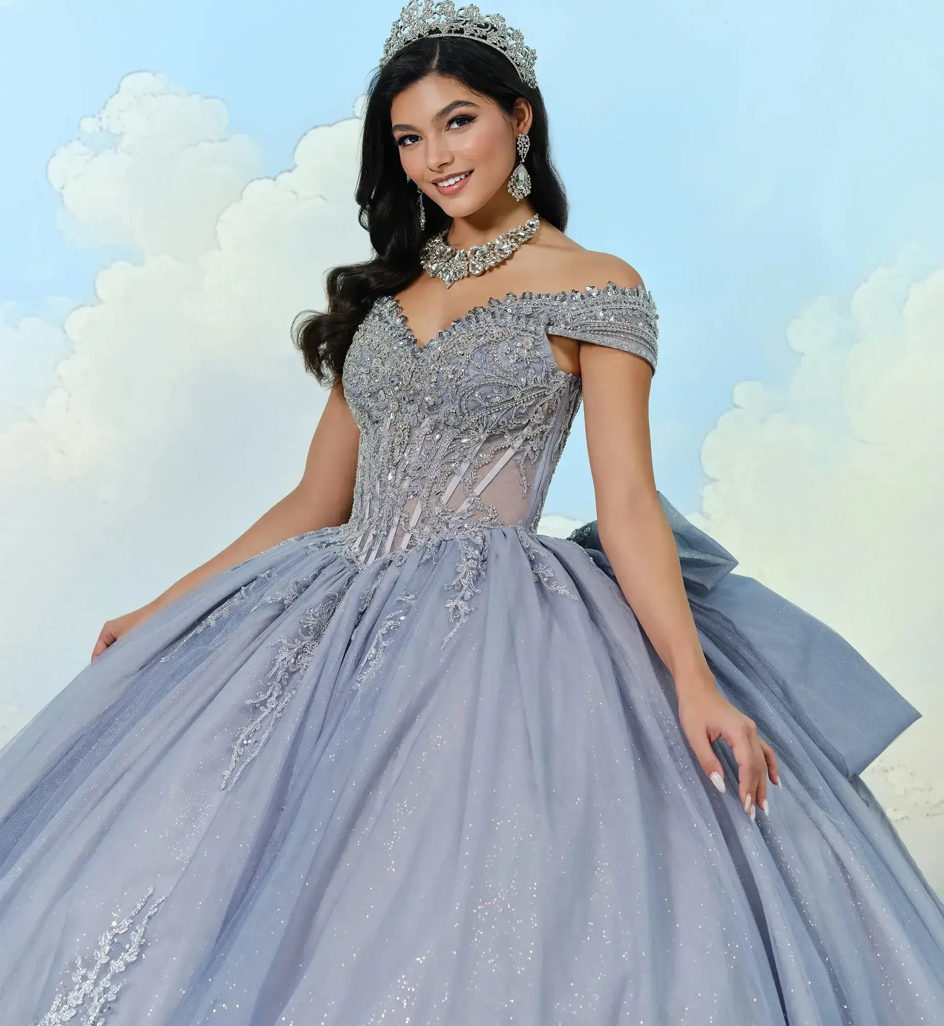 La modelo luce un vestido de quinceañera con hombros descubiertos y efecto niebla plateada.