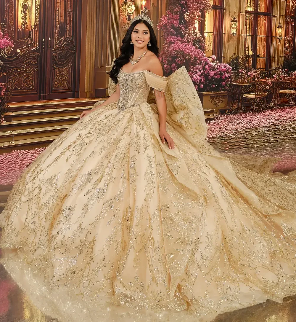Una mujer que viste un lujoso y ornamentado vestido dorado se encuentra en un entorno elegante, con grandes puertas y decoraciones florales.