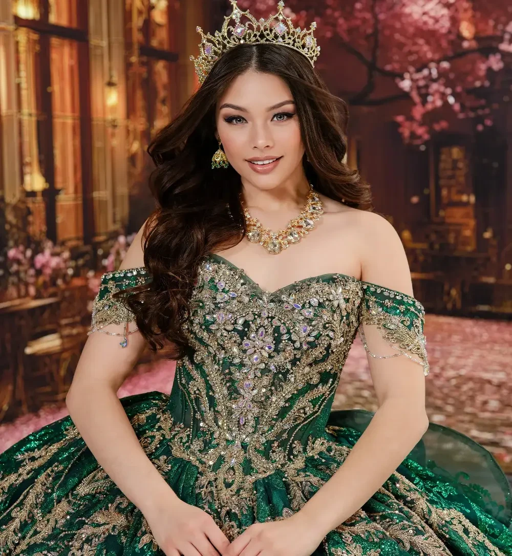 Una mujer que viste un vestido verde con los hombros descubiertos, adornado con detalles intrincados y una corona, de pie en un entorno bellamente decorado.