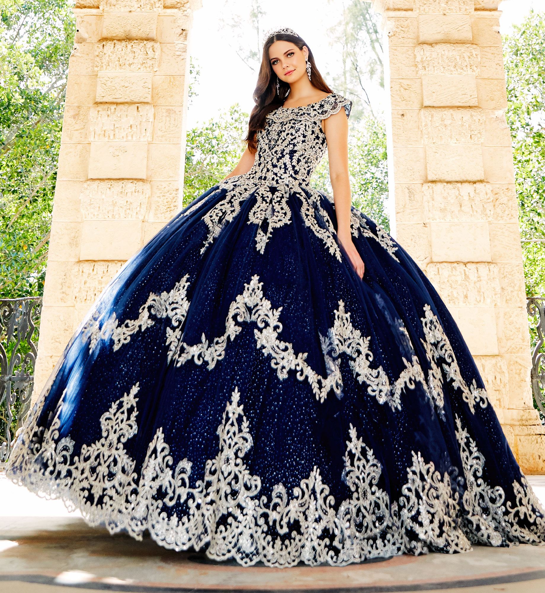 Brunette model in dark blue quinceañera dress with silver lace embroidery