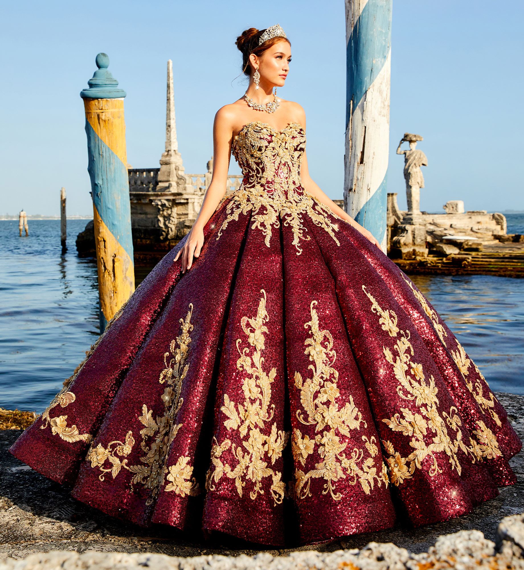 Brunette model at seaside wearing red and gold quinceañera dress